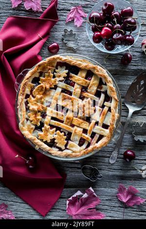 Top down view of a freshly baked lattice cherry pie on a rustic wooden table. Stock Photo