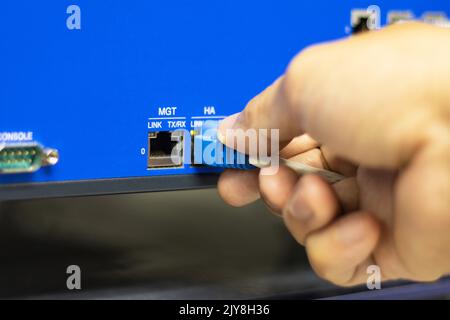 Hand of a man holding The network cables to connect the port of a switch to connect internet network, concept Communication technology Stock Photo