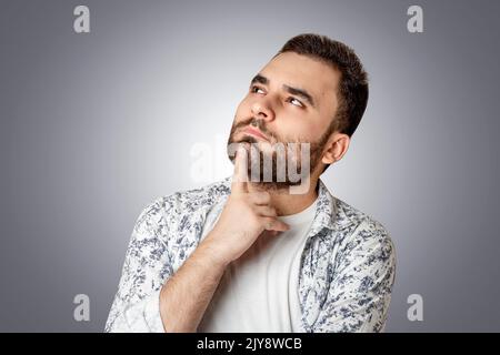 A person thinking and looking up, putting his hand to his face, isolated background Stock Photo
