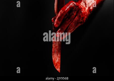 Man holding knife with bloody hand on black background.  Stock Photo