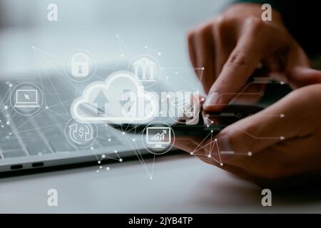 A guy works on a laptop with a cloud computing diagram. Cloud computing and internet service principles. Stock Photo