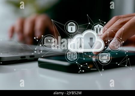 With a cloud computing diagram shown on a laptop, a man works on his computer. Networking and internet service principles and cloud computing technolo Stock Photo