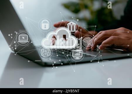 With a cloud computing diagram in hand, a man uses his laptop. Infrastructural principles such as data storage, networking, and the internet. Stock Photo