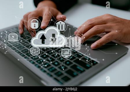 A man works on a laptop that has a diagram of cloud computing on it. Cloud technology is a way to store and access data through a network and the inte Stock Photo