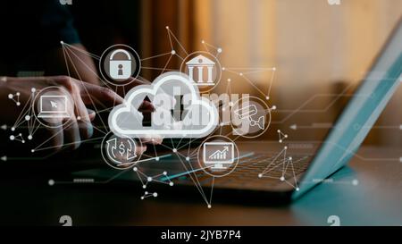 A guy works on a laptop while holding a cloud computing diagram. Concepts of cloud computing, data storage, networking, and internet services. Stock Photo