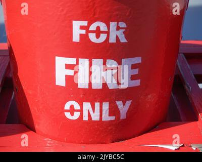 Bright red buckets labeled in white For Fire Only ready as protection in case of fire., Stock Photo