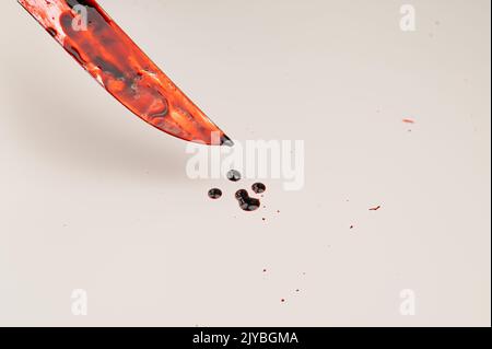 Close-up of a sharp knife covered in blood on a white background. Stock Photo
