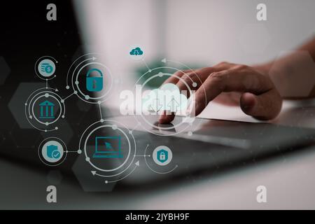 A man uses a laptop with a cloud computing schematic. Cloud computing is a type of technology that allows you to store. Storage of information. Concep Stock Photo