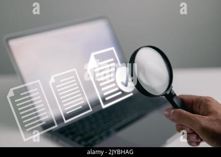 Documents and magnifying glass. Confirmed or approved document on laptop computer. Stock Photo