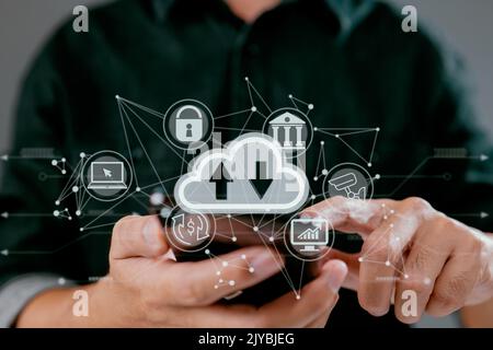 A guy uses a smartphone while holding a cloud computing diagram. Data storage, networking, and internet service principles are all part of cloud techn Stock Photo