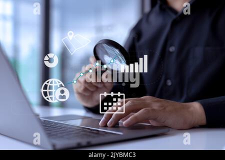 Business analyst with magnifying glass analyzing graphs and charts for market expansion, financial reports, investment data, or sales information conc Stock Photo