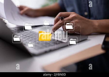 Based on electronic documents, the paperless office concept. While looking at icons for electronic documents on a virtual screen, a businessman types Stock Photo