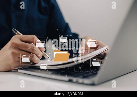 Electronic-document-based paperless office concept. A businessman types while looking at icons for electronic documents on a virtual screen while usin Stock Photo