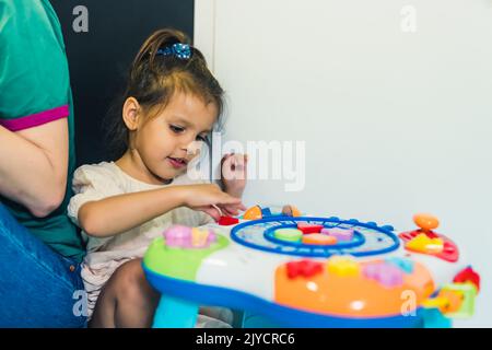 Toddler girl playing with educational sensory toys at the nursery school. Imagination and critical lifelong skills development, conflict resolution teaching Stock Photo