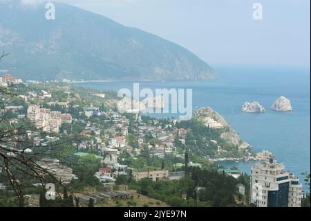 Resort town Gurzuf, buildings beach sea mountains plunged in a fog, cloudy sky, landscape. Southern coast of the Black Sea, Crimea. Stock Photo