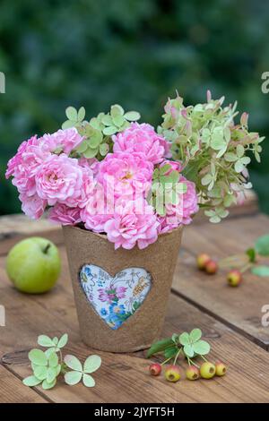 bouquet of pink roses and hydrangea flowers in biodegradable pot with heart ornament Stock Photo