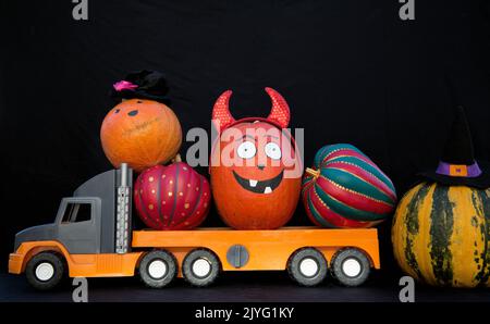 big kids toy truck loaded with lots of beautiful orange pumpkins. Preparation and delivery of decor for the terrible Halloween holiday. Festive street Stock Photo