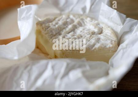 camembert cheese in unwrapped paper Stock Photo