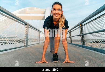 Young sport woman stretching and preparing to run outdoors in city Stock Photo