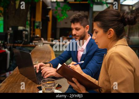 Two business guys are working on their business project seriously, online, in a cafe bar, on a beautiful day Stock Photo