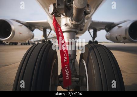 Aircraft nose wheel with red flag Remove Before Flight. Selective focus on airplane at airport. Stock Photo