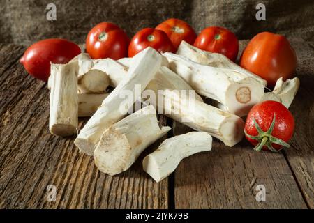 Red tomatoes and horseradish for making a spicy snack. Food on a dark background Stock Photo