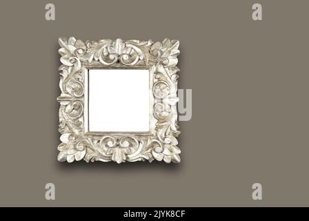 An ornate floral design square wooden frame painted in silver. Hung on wall. With clipping path Stock Photo