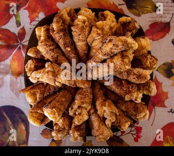 Plato de cañas fritos rellenos de crema sobre un mantel de flores Stock Photo