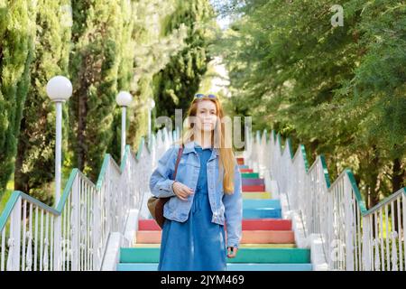 Woman on multi-colored steps. Concrete colored staircase. Blonde girl in jeans Stock Photo