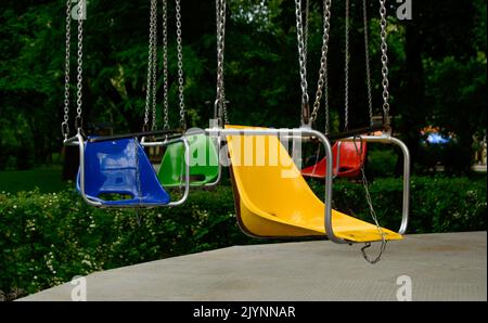 Pretty swing in a park with a different colour seats. Background picture. Stock Photo