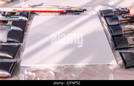 Clean empty canvas on panel and tubes of the oil paints. Creative space. Stock Photo