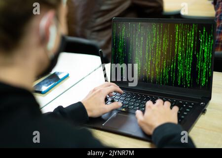 hacker writes code on laptop in matrix style Stock Photo