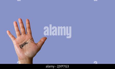 Word equal written on hand isolated on blue background. copy space Stock Photo