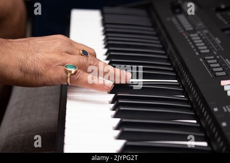 Hands Of Man Wearing Emerald Natural Panna And Blue Sapphire Neelam Gemstone Playing Notes On Piano Or Keyboard. Musical Training Or Coaching, Live Mu Stock Photo