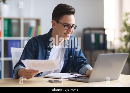 Office Work. Portrait Of Smiling Young Entrepreneur Working With Papers And Laptop Stock Photo