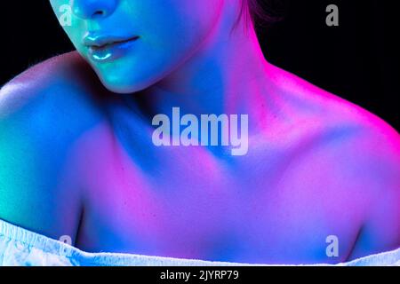 Close up female neck, collarbones and shoulders in pink neon light over dark background. Natural beauty, fitness, diet, spa, aesthetic cosmetology Stock Photo