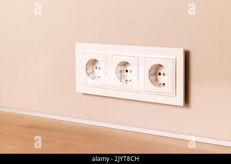 Group of white european electrical outlets on modern beige wall. Selective focus Stock Photo