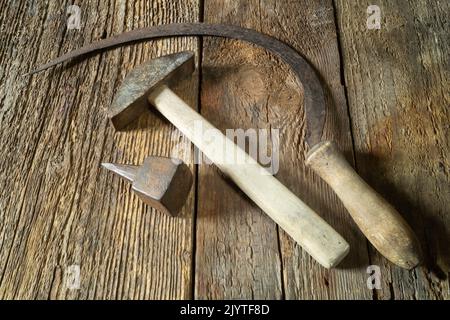 Rural tools for working in the field. A set of rusty objects. Hammer sickle and anvil on an old board Stock Photo