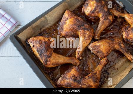 Oven roasted chicken legs on a a baking tray on white background Stock Photo