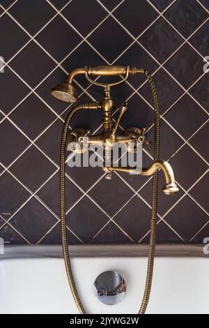 Golden faucet and shower in vintage style on a background of brown tiles Stock Photo