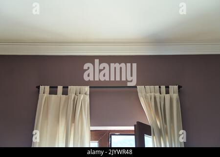 White ceiling and pink wall with part of an open window and light curtains Stock Photo
