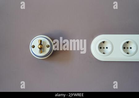 Retro style light switch and socket on dark pink wall Stock Photo