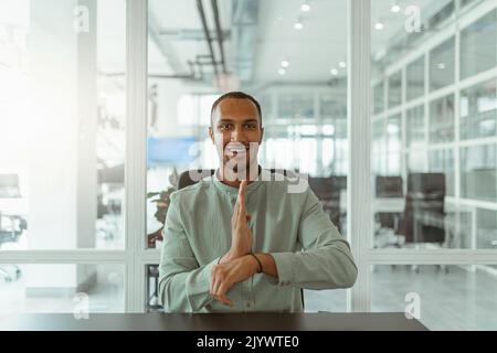 African businessman using sign language while talking online with client sitting in office Stock Photo