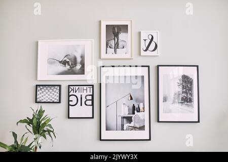 different size framed photos hanging on the gray wall. Stock Photo