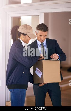 Please sign here. a mature well dressed man receiving a package and signing it in his home. Stock Photo
