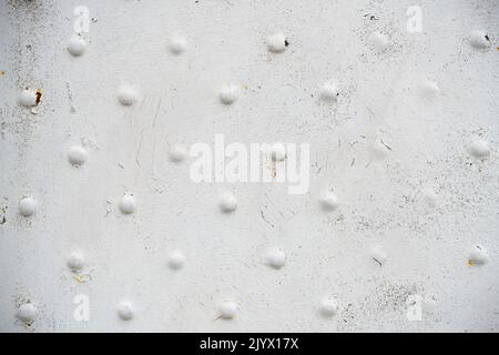 Old metal surface with rivets with white peeling paint Stock Photo