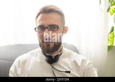 Head shot portrait close up smiling confident businessman wearing glasses looking at camera, standing in modern cabinet, successful happy young man Stock Photo