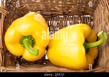 Two sweet peppers of bright yellow color in a basket, macro. Stock Photo