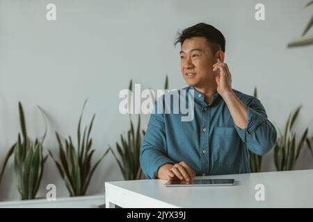 Confident asian businessman working on digital tablet while sitting in cozy office Stock Photo