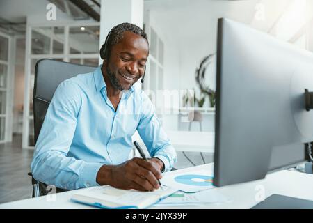 Smiling African businessman taking while working on computer in modern office Stock Photo